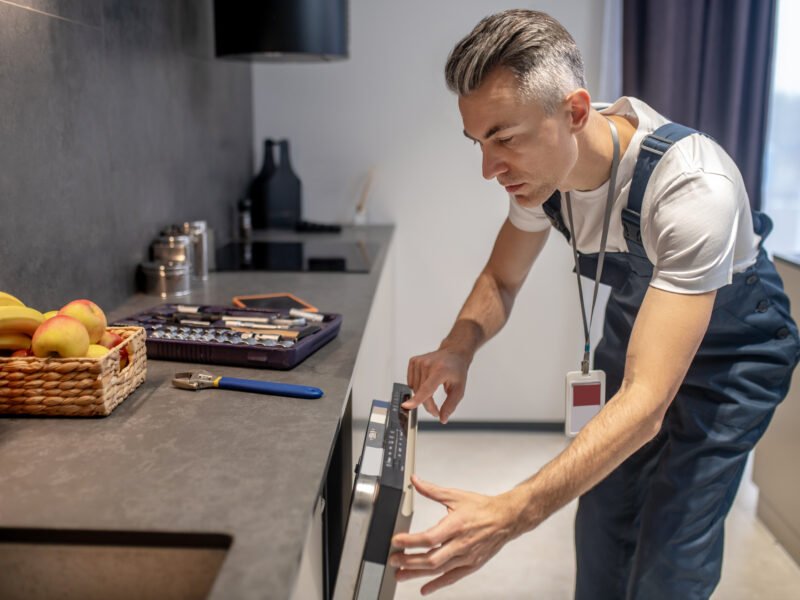 Man looking at information on control panel of dishwasher