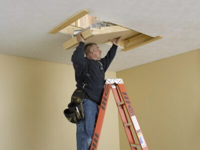 A handyman installs an attic ladder