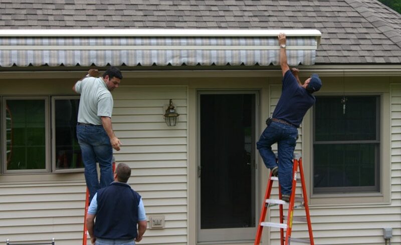 A handyman repairs awning