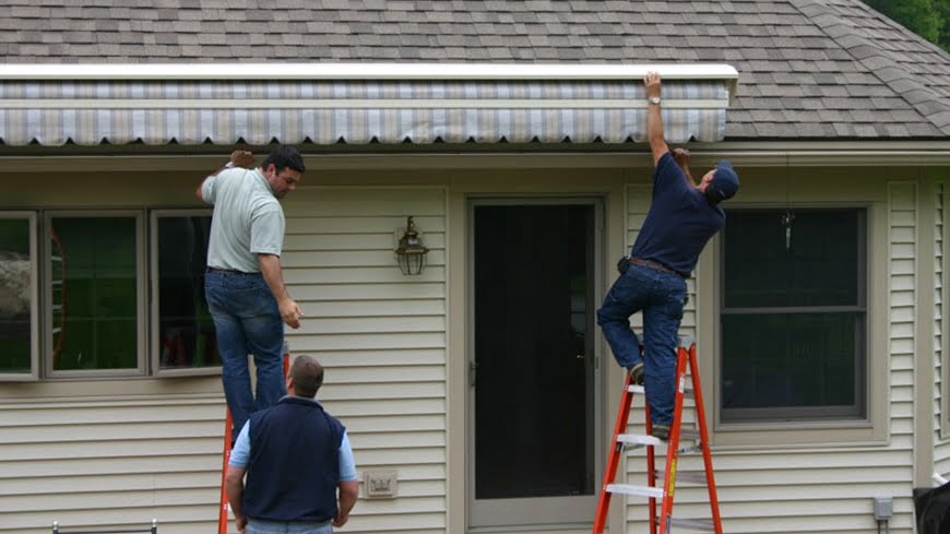 A handyman repairs awning