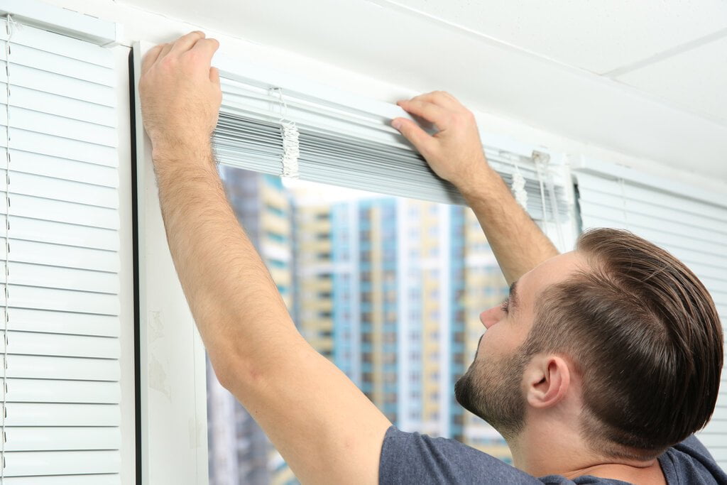 A handyman installs blinds