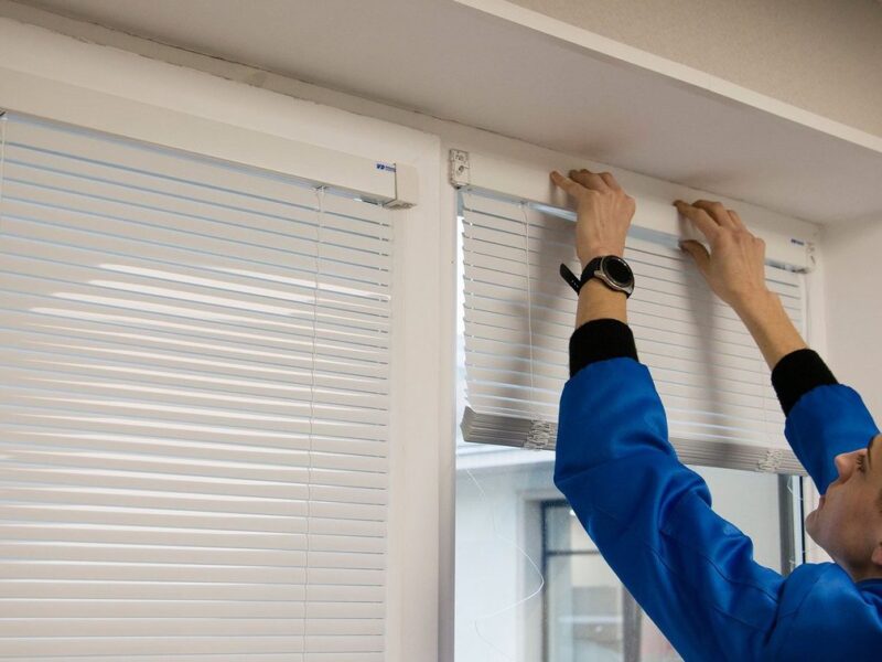 A handyman repairs blinds