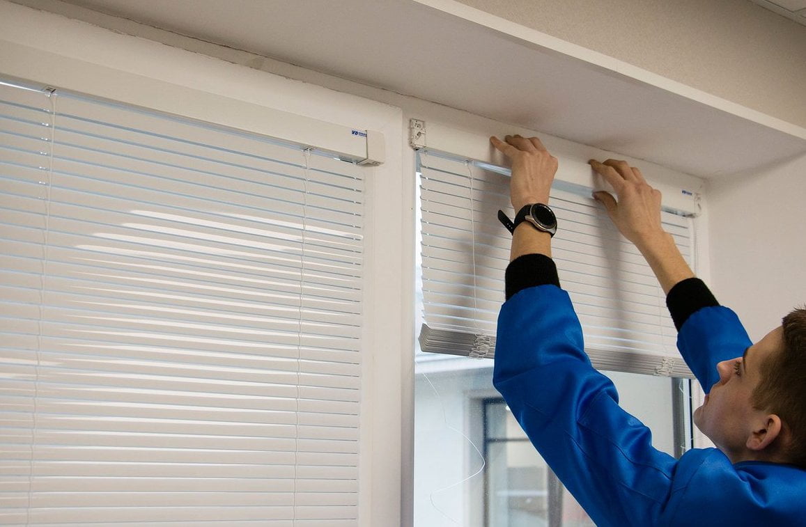 A handyman repairs blinds