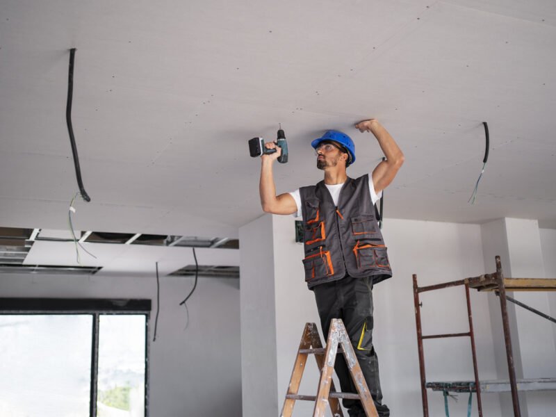 A handyman repairs the ceiling