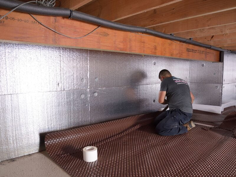 A worker repairs a crawlspace