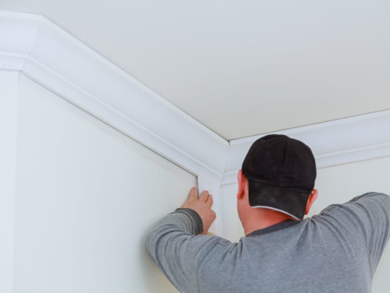 A handyman installs crown molding