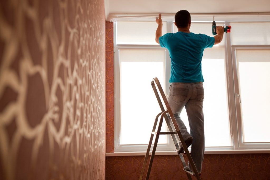 A handyman hangs curtain rod