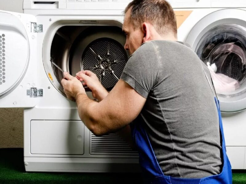 A handyman repairs a dryer
