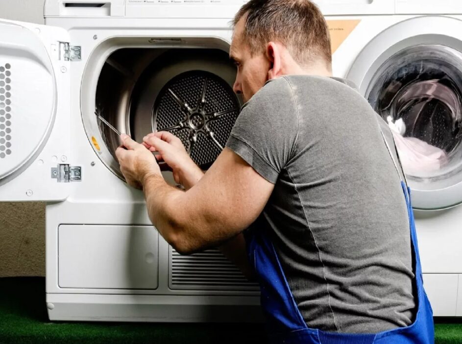 A handyman repairs a dryer