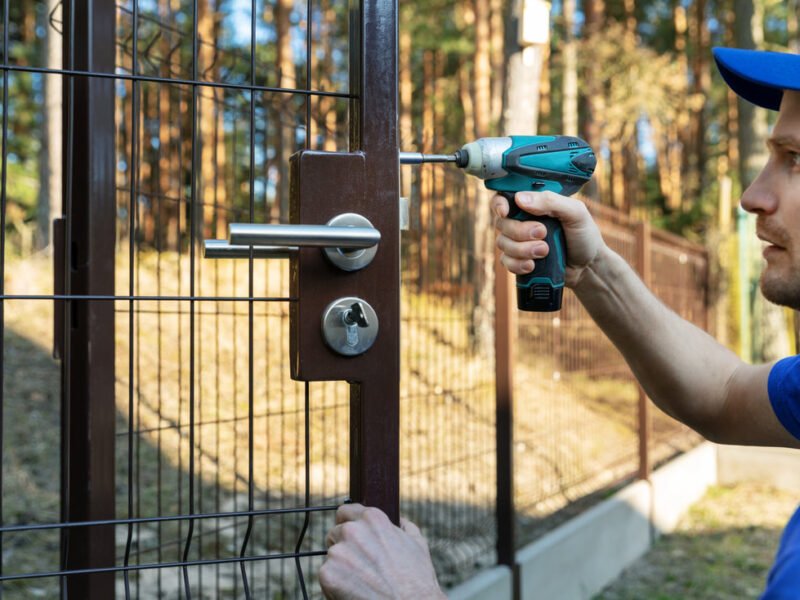 A handyman repairs a gate
