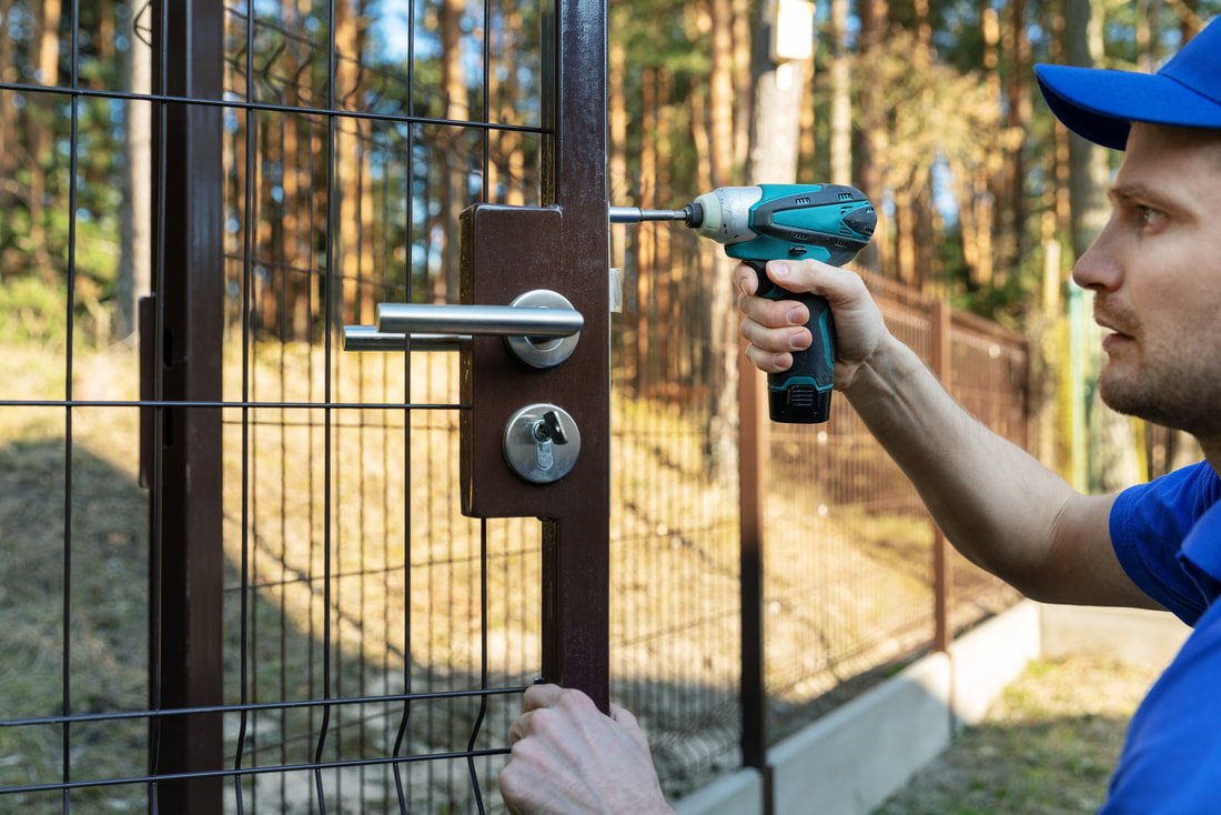 A handyman repairs a gate