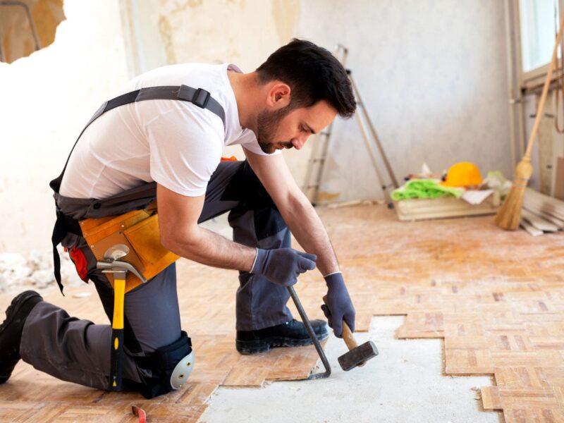 A handyman repairs a floor