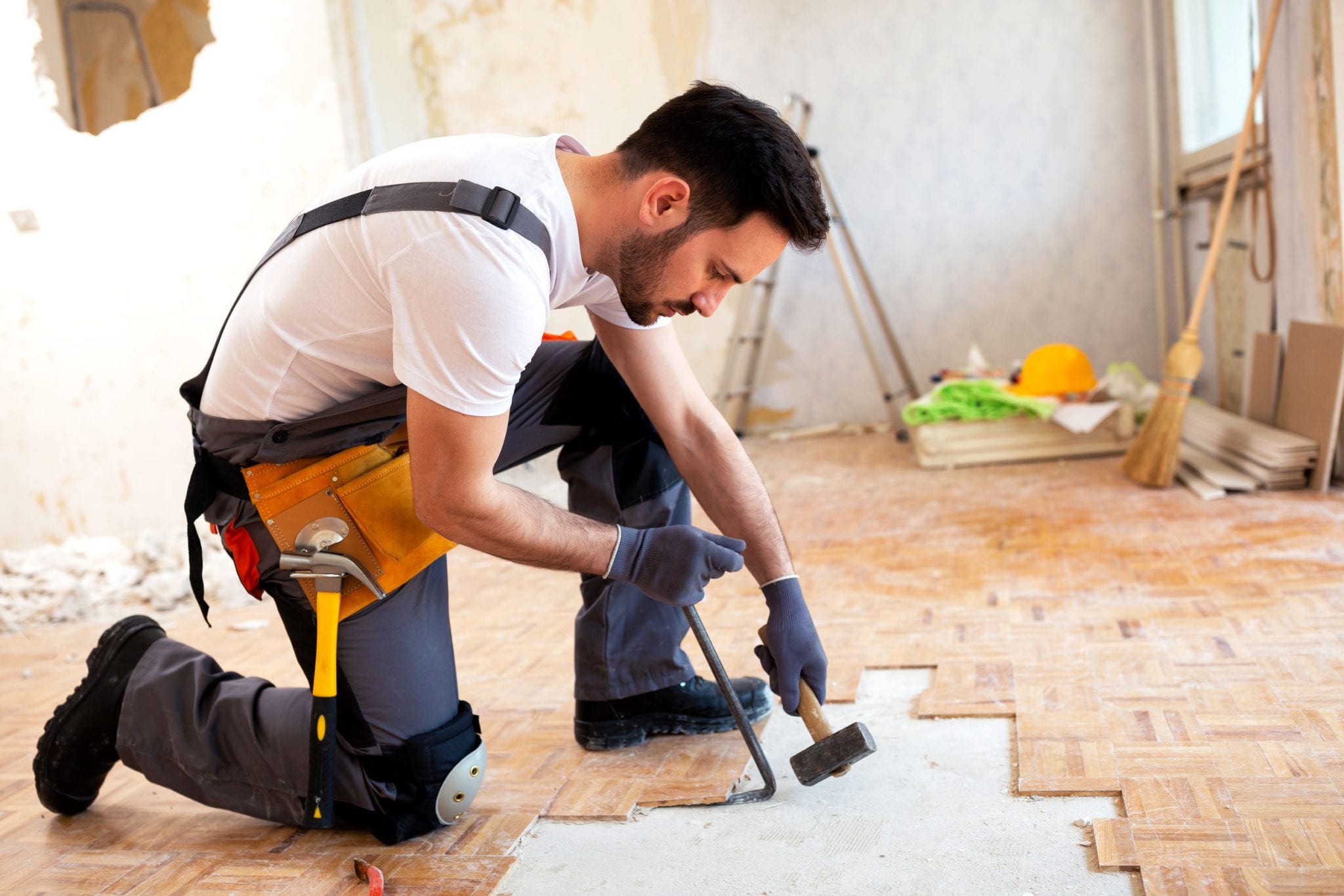 A handyman repairs a floor