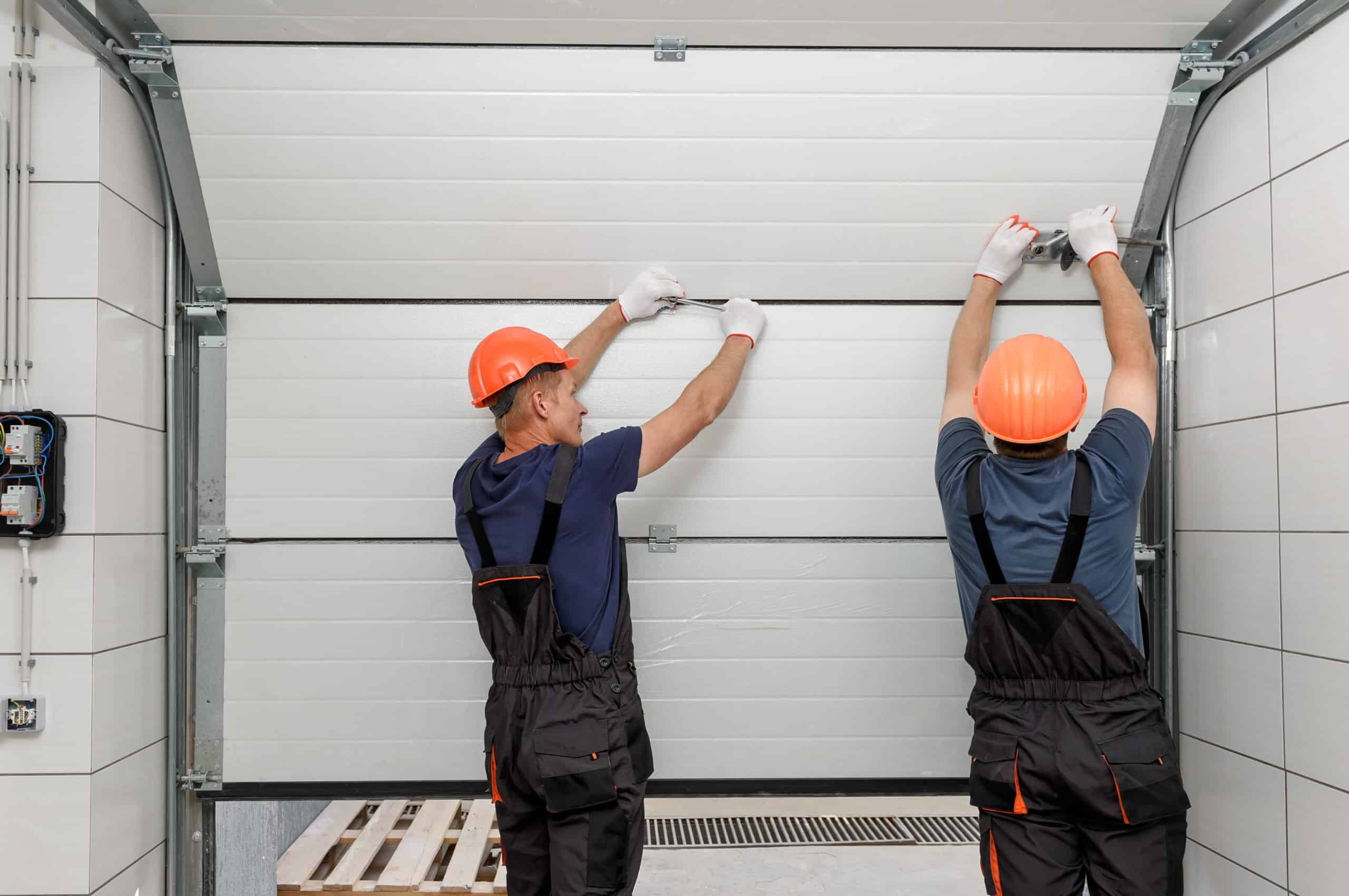 Handymen repair a garage door