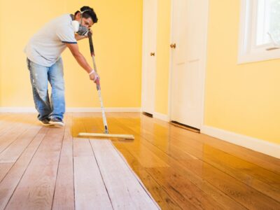 A handyman finishes a hardwood floor