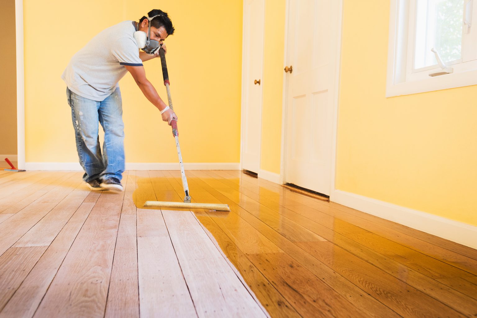 A handyman finishes a hardwood floor