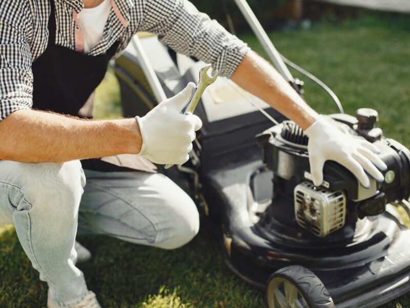 A handyman repairs a lawnmower