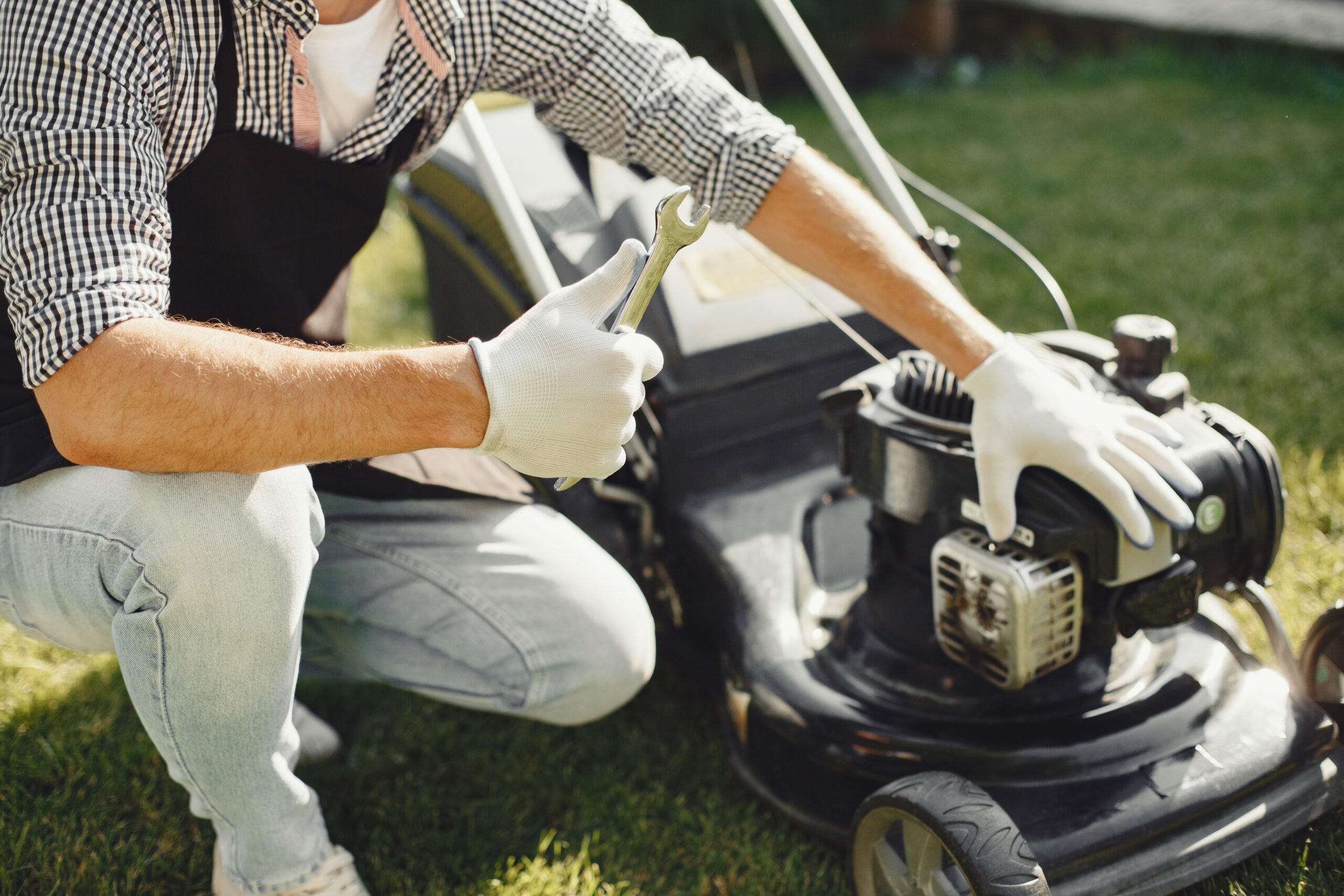 A handyman repairs a lawnmower