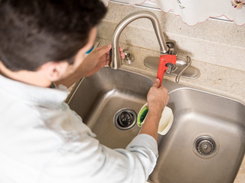 A plumber repairs a leaky faucet