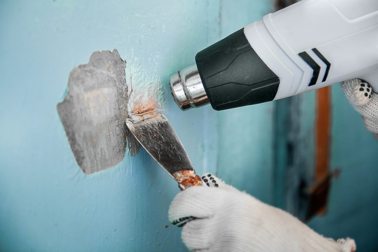 A handyman removes a paint