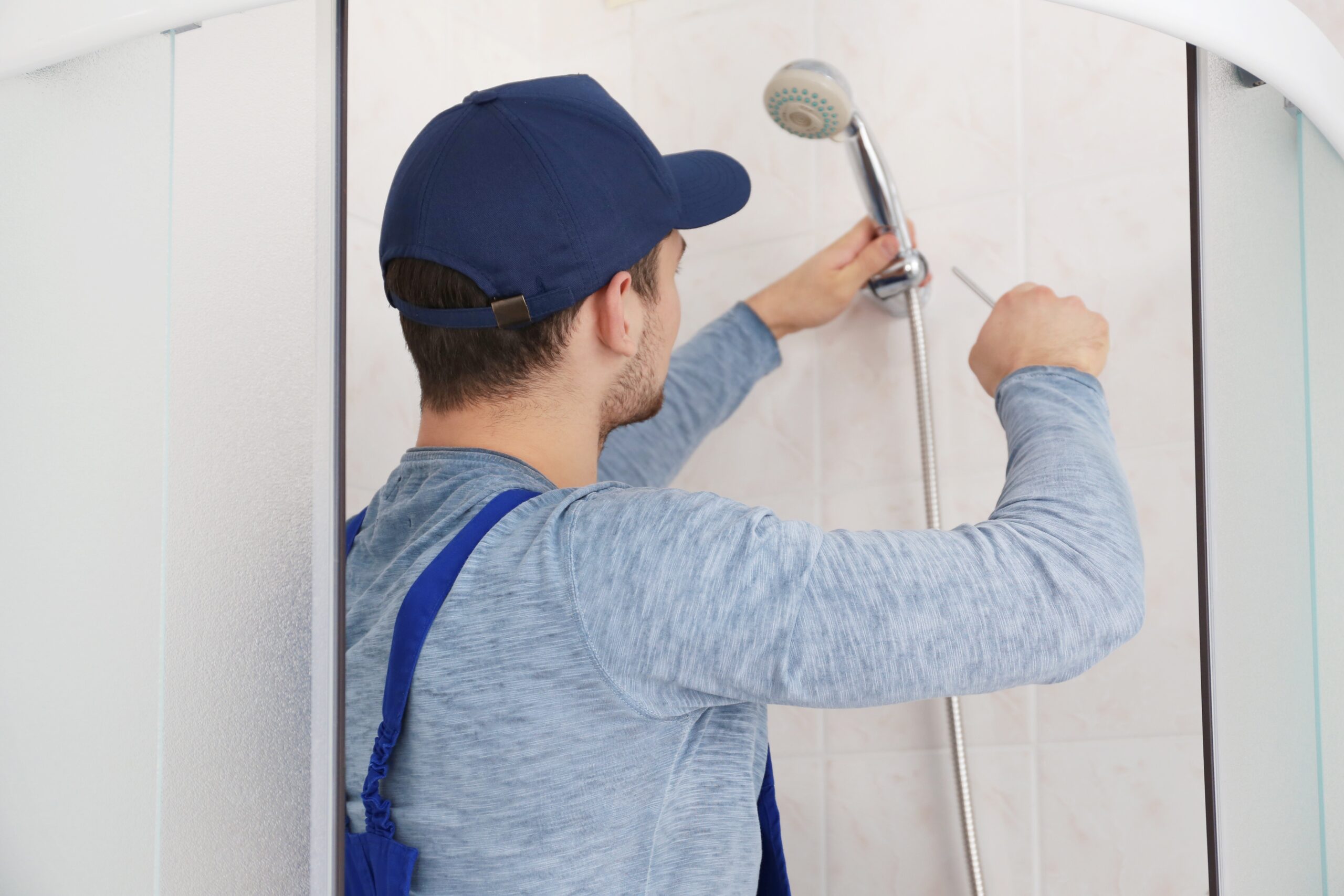 A handyman repairs a shower