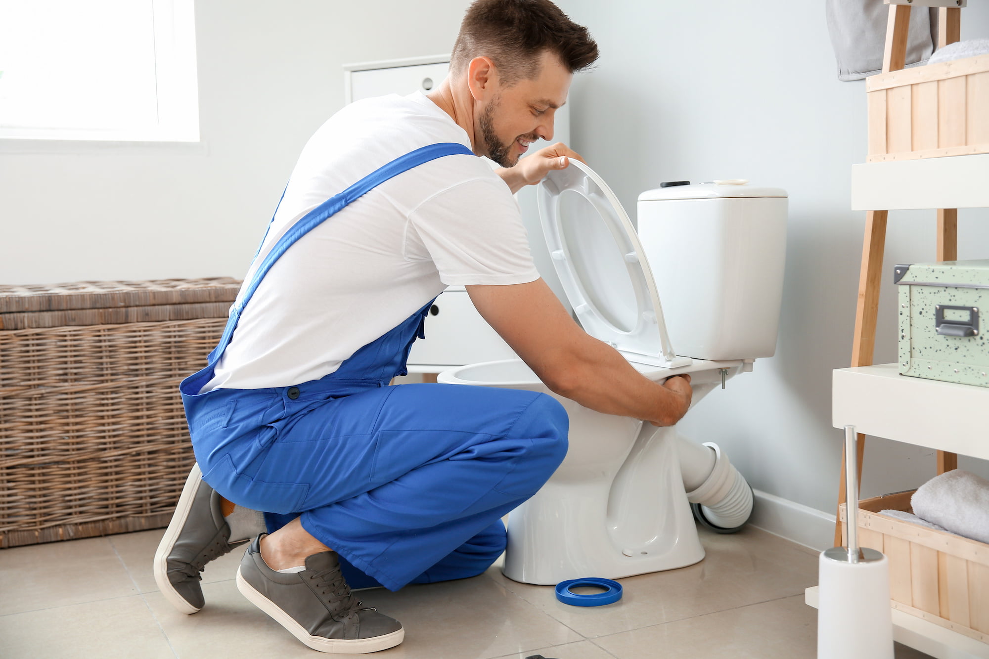 A plumber installs toilet in restroom