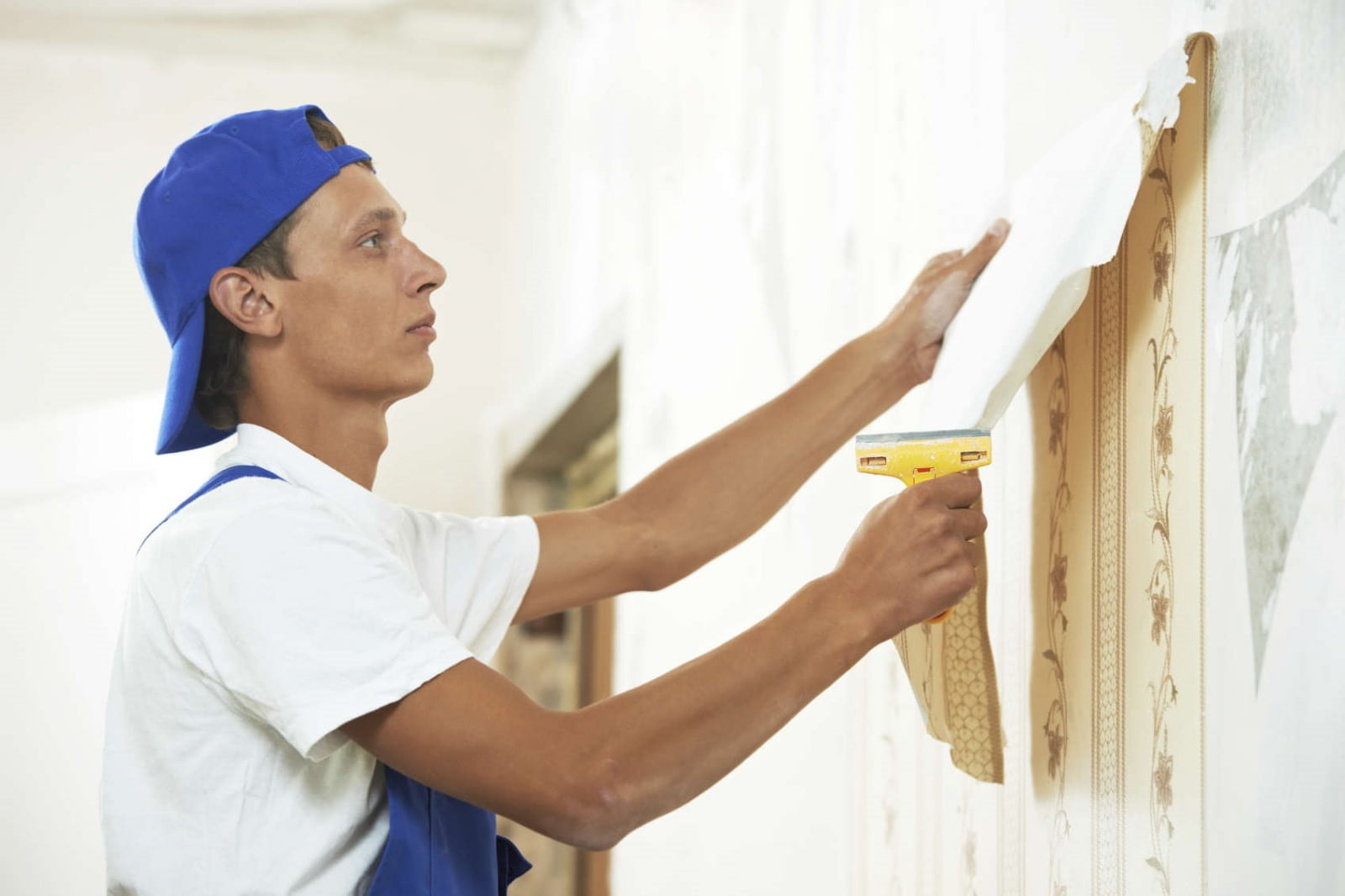 A handyman removes wallpapers