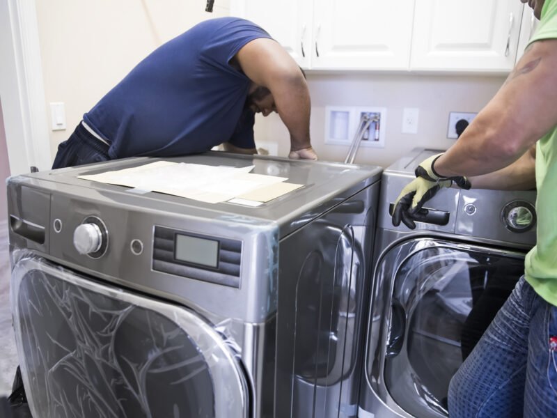 Workers install a washer and a dryer