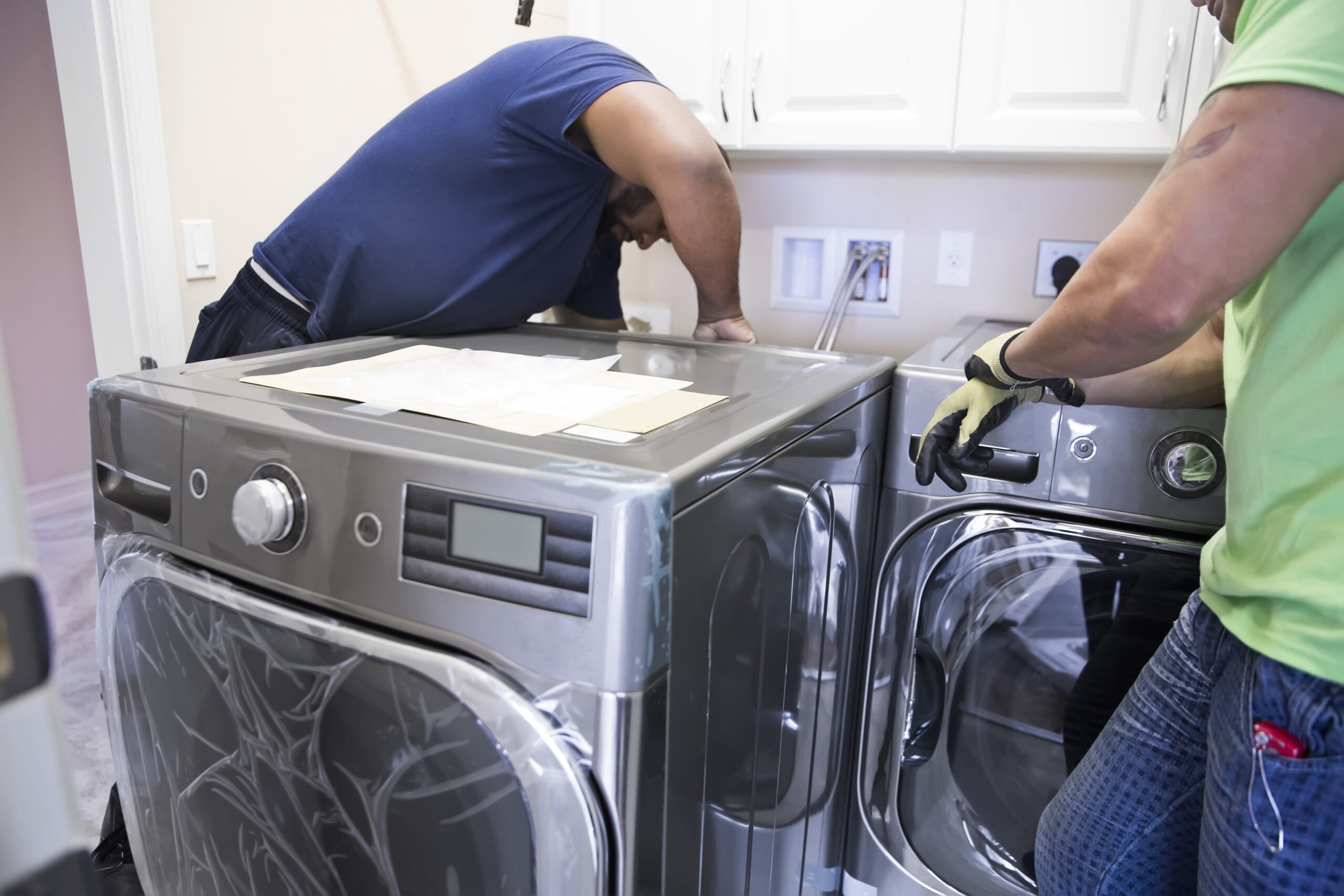 Workers install a washer and a dryer