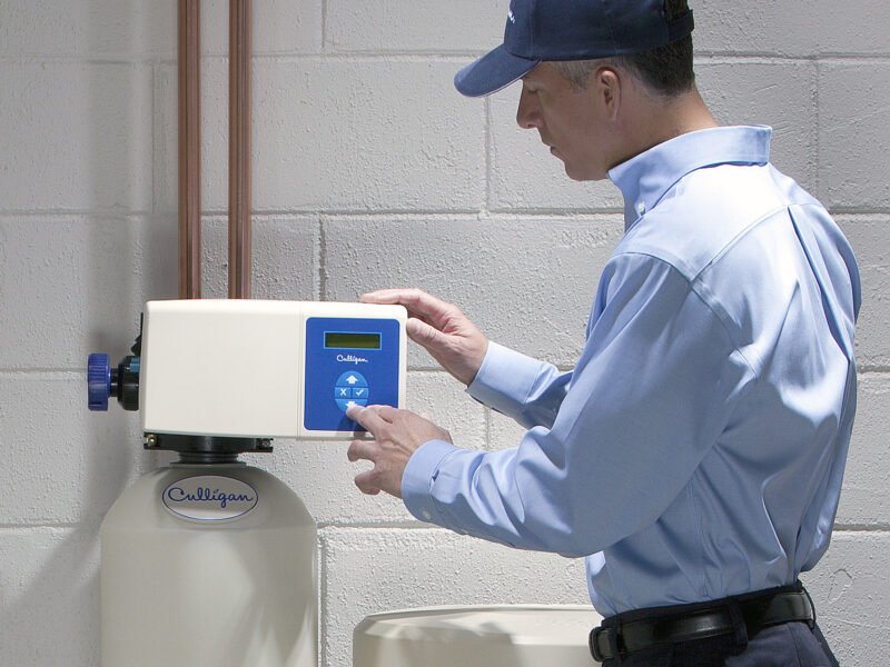 A handyman repairs a water softener