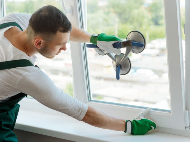 A handyman changes a window glass pane
