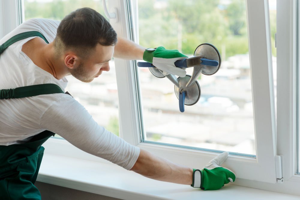 A handyman changes a window glass pane