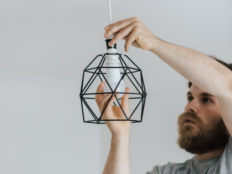 man installing light bulb in apartment