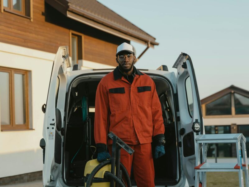 man in orange jacket standing beside white van